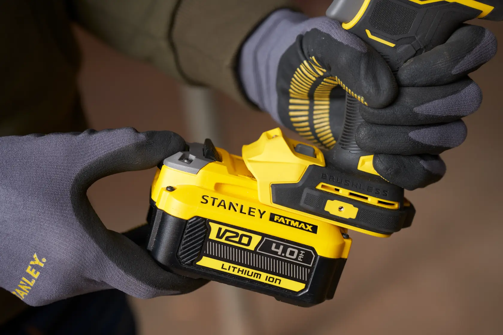 Photo of STANLEY SFMCF940B V20 4.0Ah lithium-ion battery being attached to a cordless tool, close-up view.