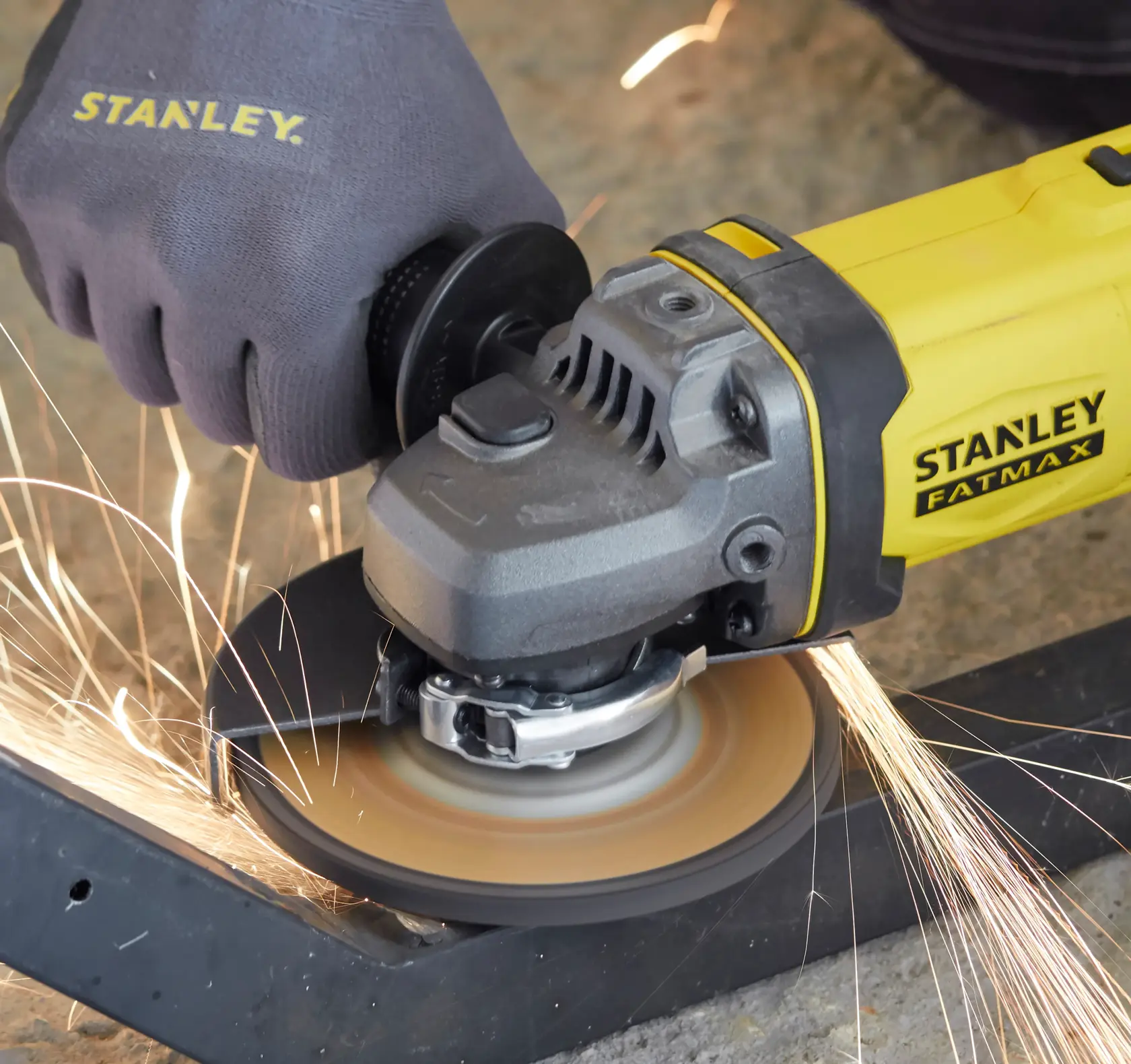 STANLEY SFMCG400B angle grinder cutting metal, yellow and black, sparks flying, close-up.