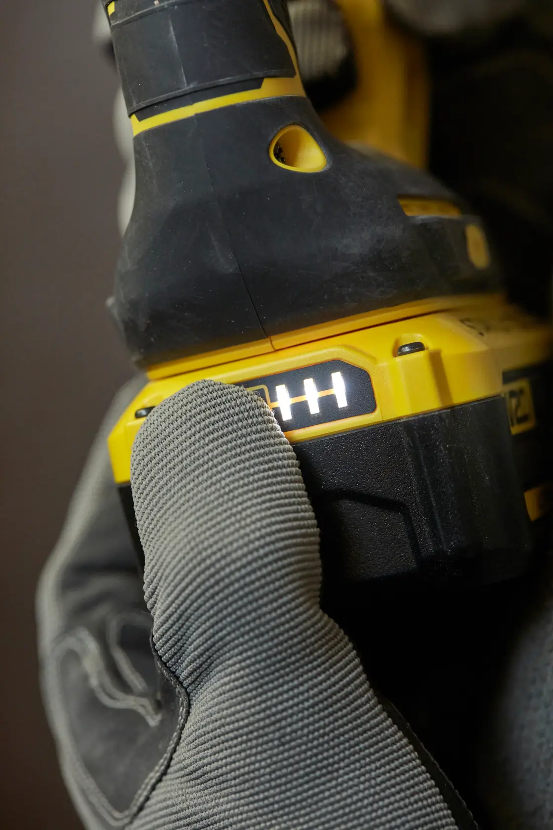 STANLEY SFMCH900B power tool close-up, battery indicator lit, glove pressing button, side angle.