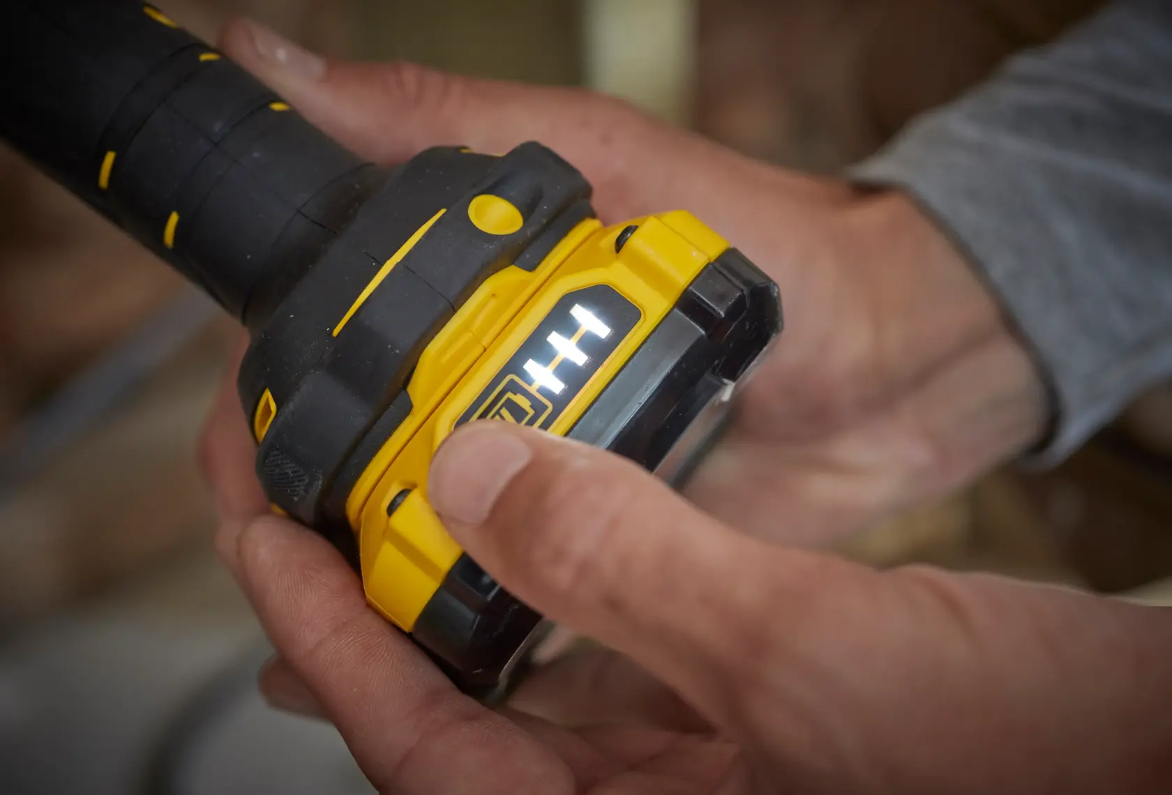 STANLEY SFMCL020B yellow and black tool battery with LED indicator held in hand, close-up photography.