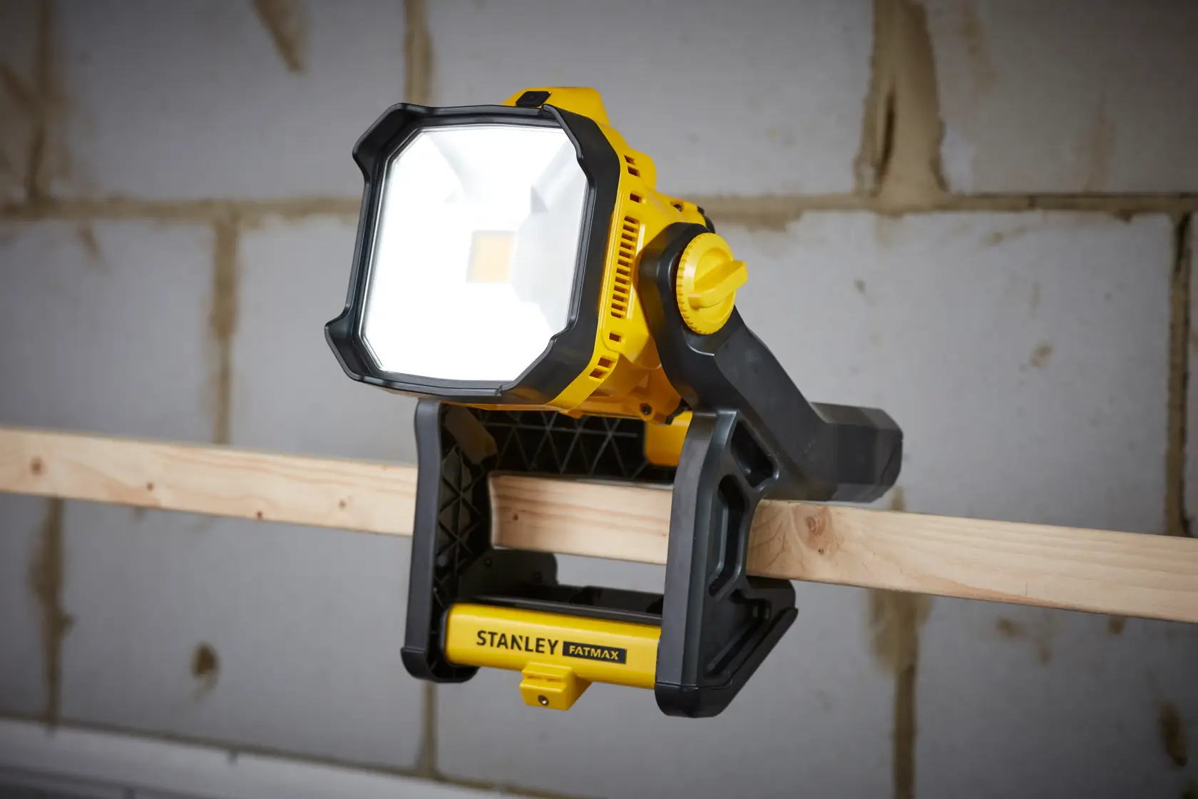 STANLEY SFMCL030B yellow and black LED work light clamped to wood beam, shown from front angle.