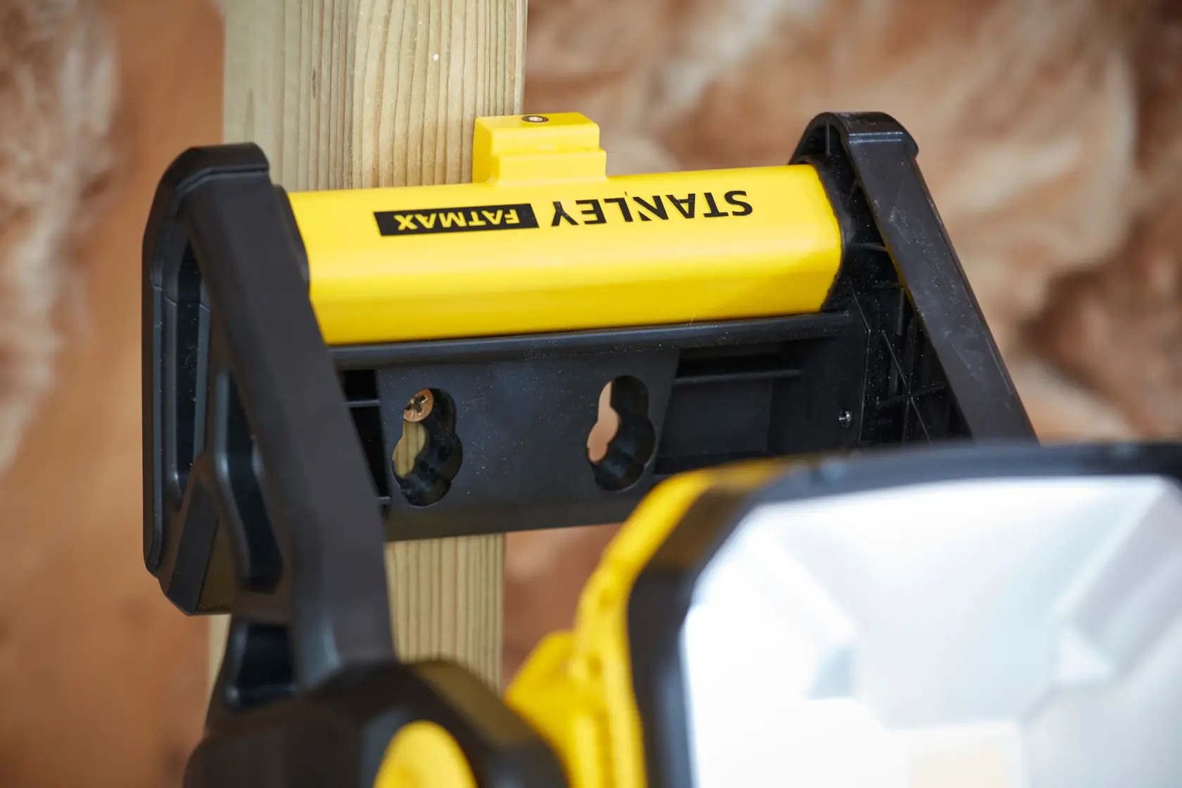 STANLEY SFMCL030B work light mounted on wooden post, close-up angle, yellow and black body.