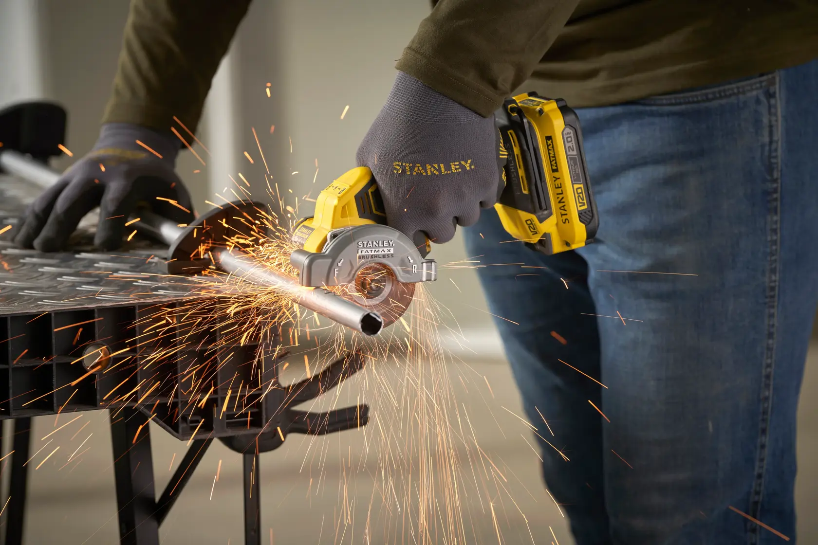 STANLEY SFMCM300B compact cordless metal cutter in use, cutting metal pipe, close-up with sparks.