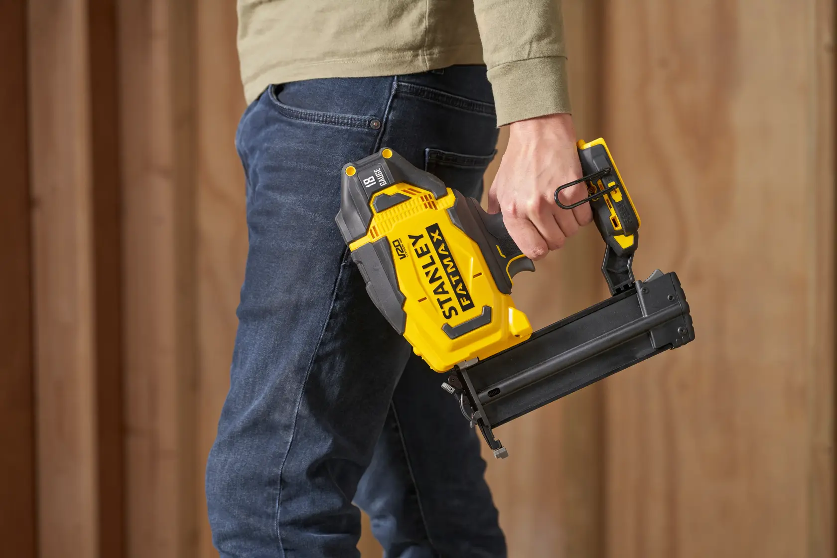 Photo of STANLEY SFMCN618B-XJ cordless yellow nail gun, held in hand, shown in side view.