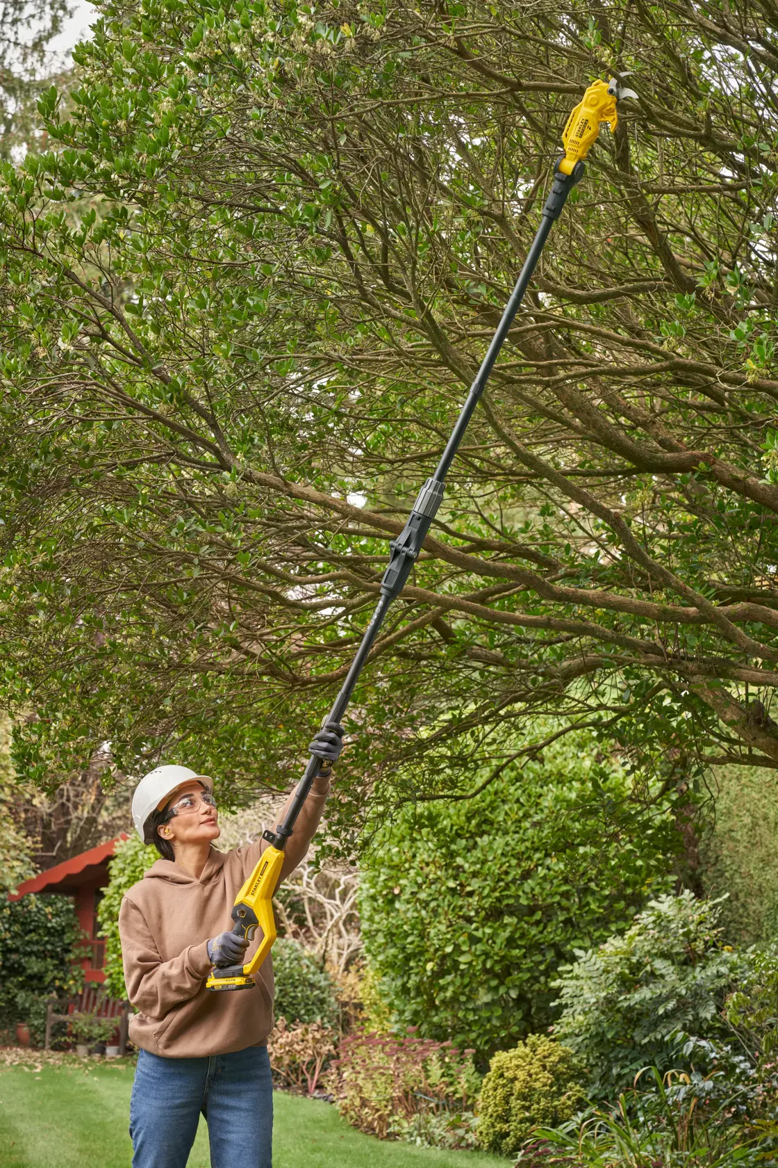STANLEY SFMCPP632D1 pole saw used outdoors for tree trimming, yellow and black design, photography.