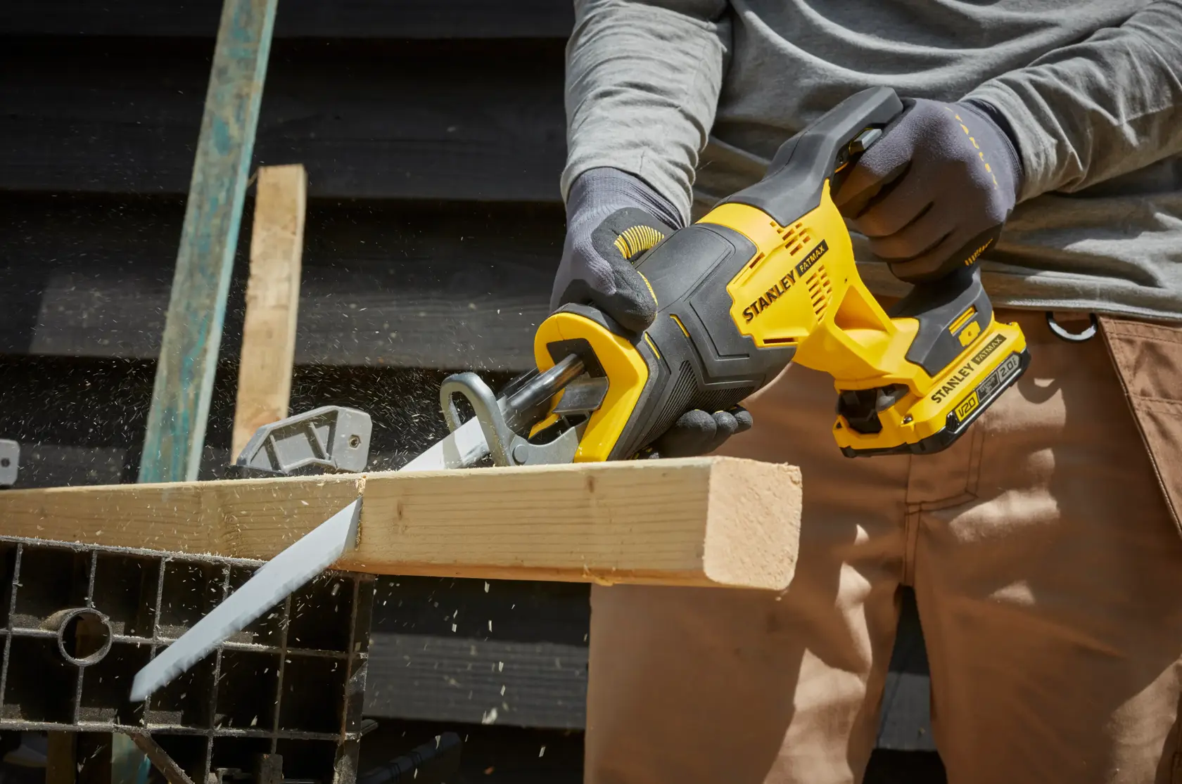 STANLEY SFMCS300B cordless reciprocating saw in use cutting wood, close-up view of power tool.