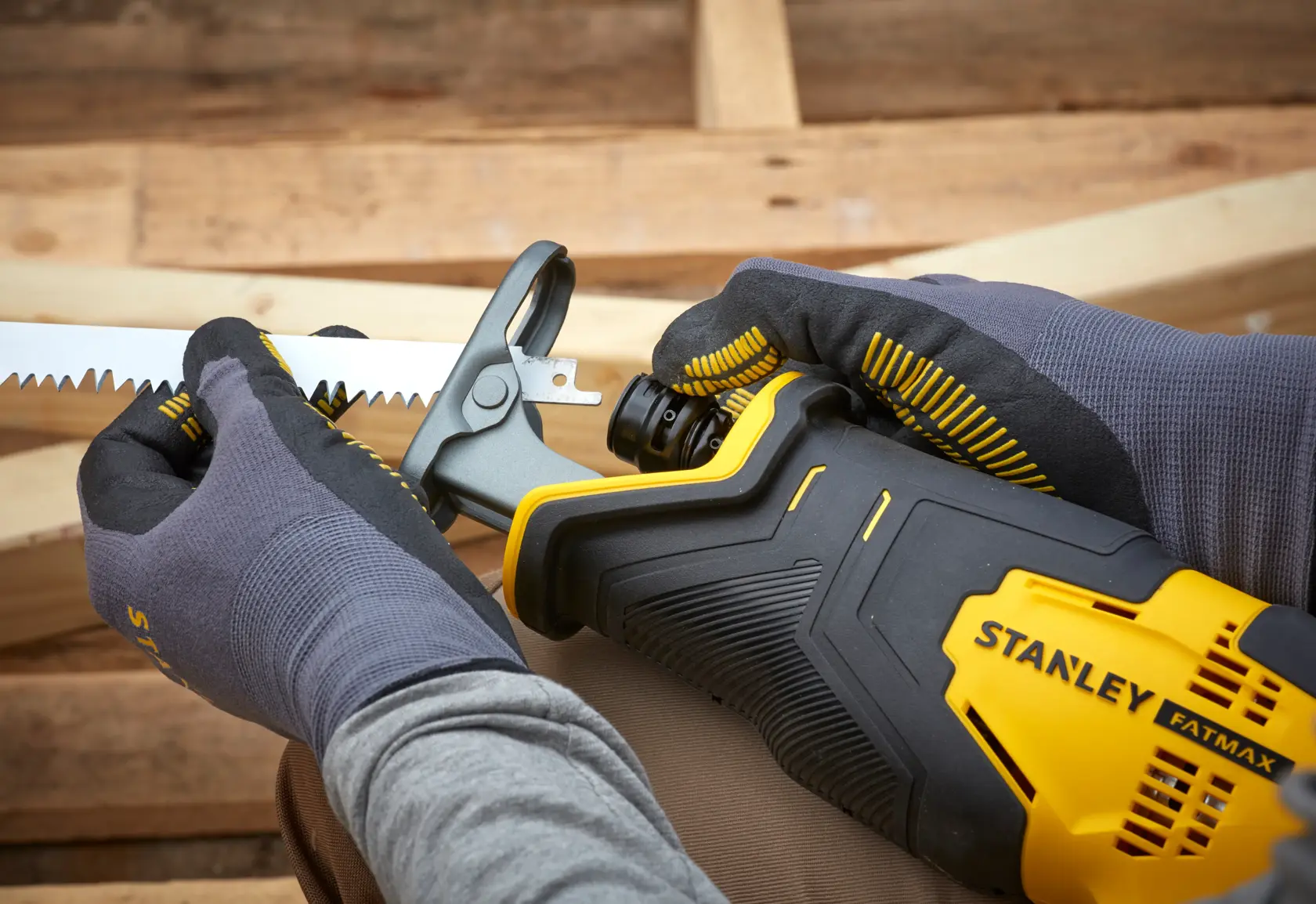 Stanley SFMCS300B reciprocating saw, close-up of blade installation, yellow and black, gloved hands.