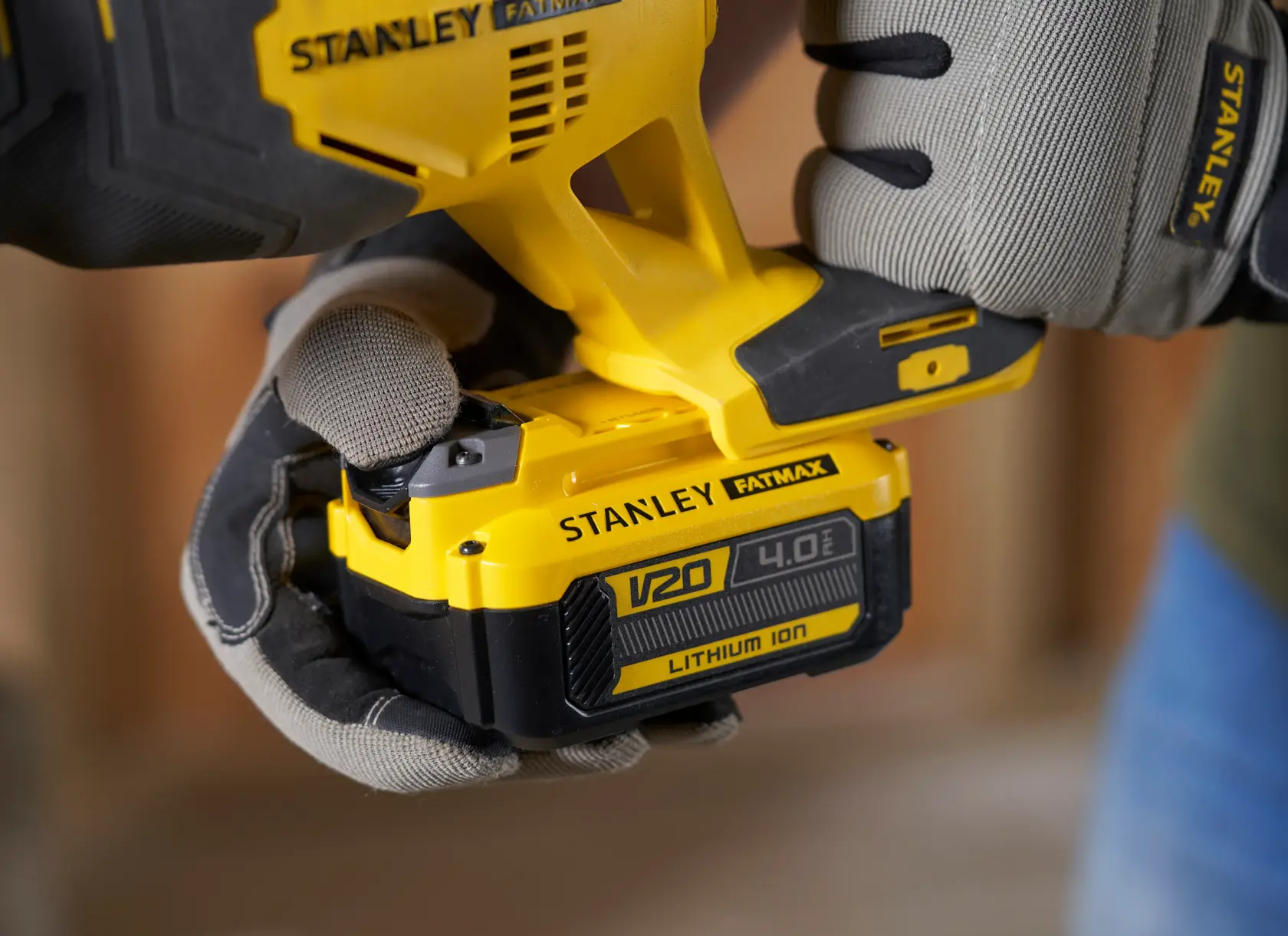 Photo of STANLEY SFMCS300B power tool with V20 4.0Ah lithium ion battery being held by gloved hands.