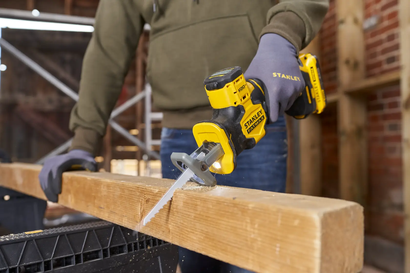 Photo of STANLEY SFMCS305B cordless reciprocating saw cutting wood beam on construction site.