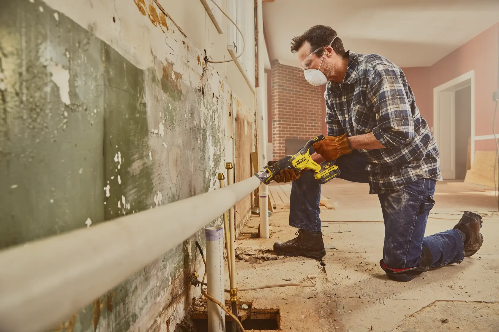 STANLEY SFMCS310B reciprocating saw used by worker cutting pipe in renovation setting.