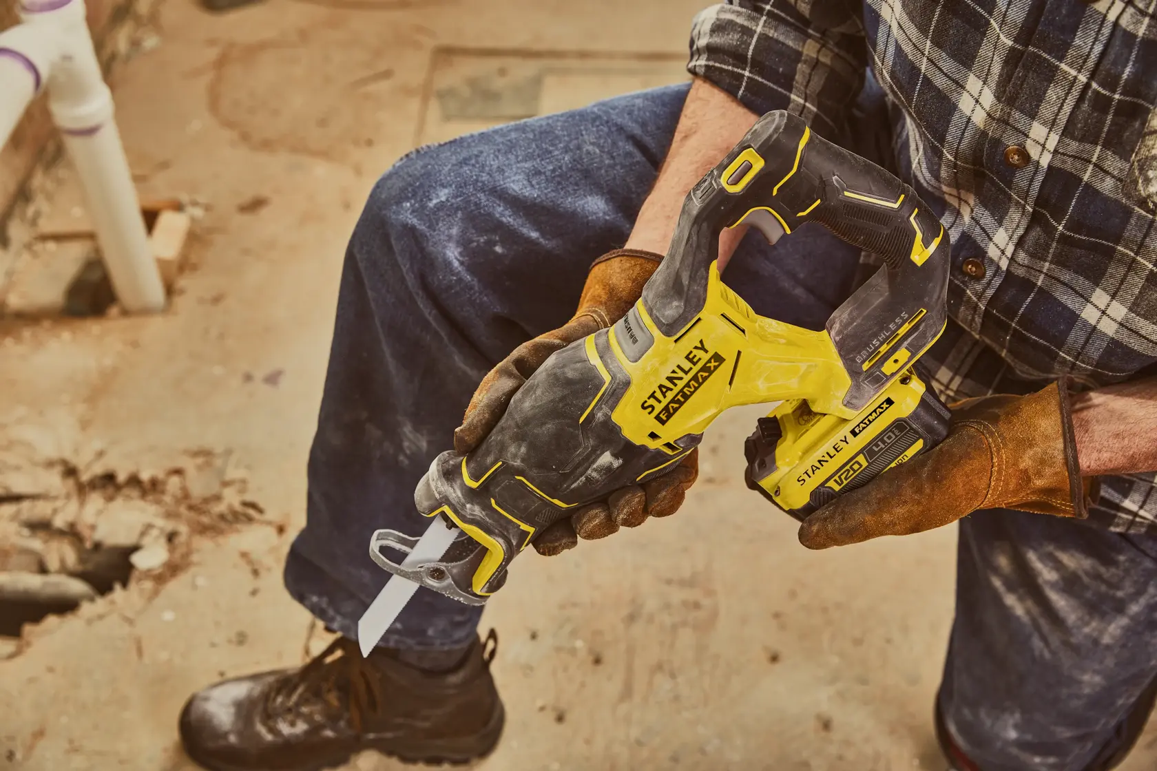 STANLEY SFMCS310B reciprocating saw held by worker on construction site, yellow and black body.