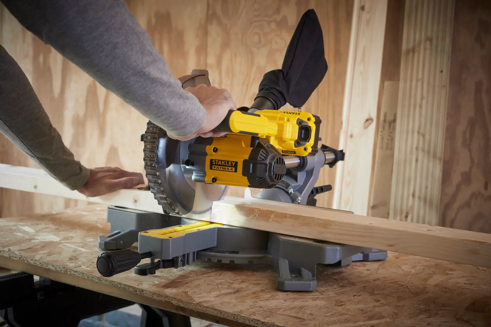 STANLEY SFMCS701M2 miter saw cutting wood, side angle, yellow and black tool in workshop.
