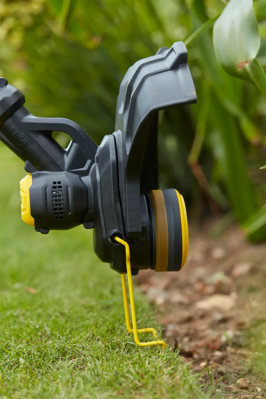 STANLEY SFMCST933M1 grass trimmer head close-up, showing yellow line guide on lawn edge.