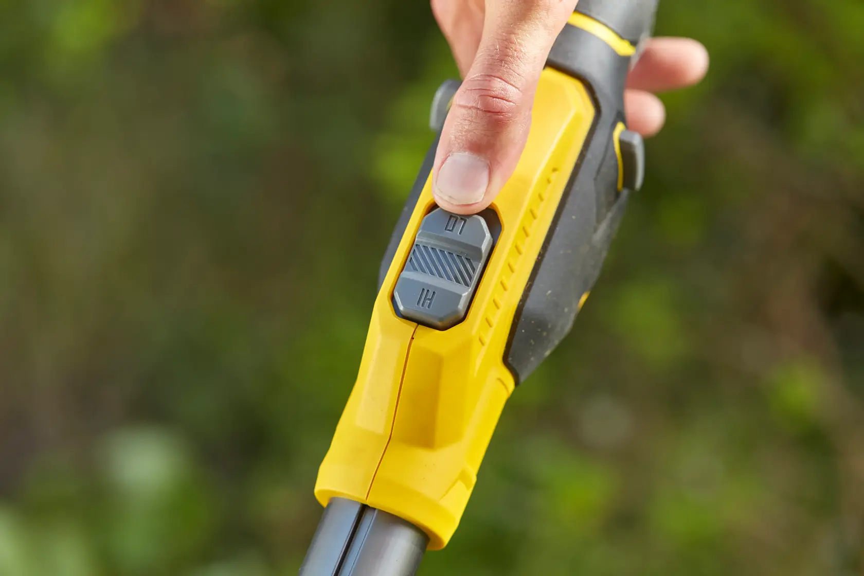 Photo of STANLEY SFMCSTB933M grass trimmer handle close-up showing yellow grip and dual-speed control switch.