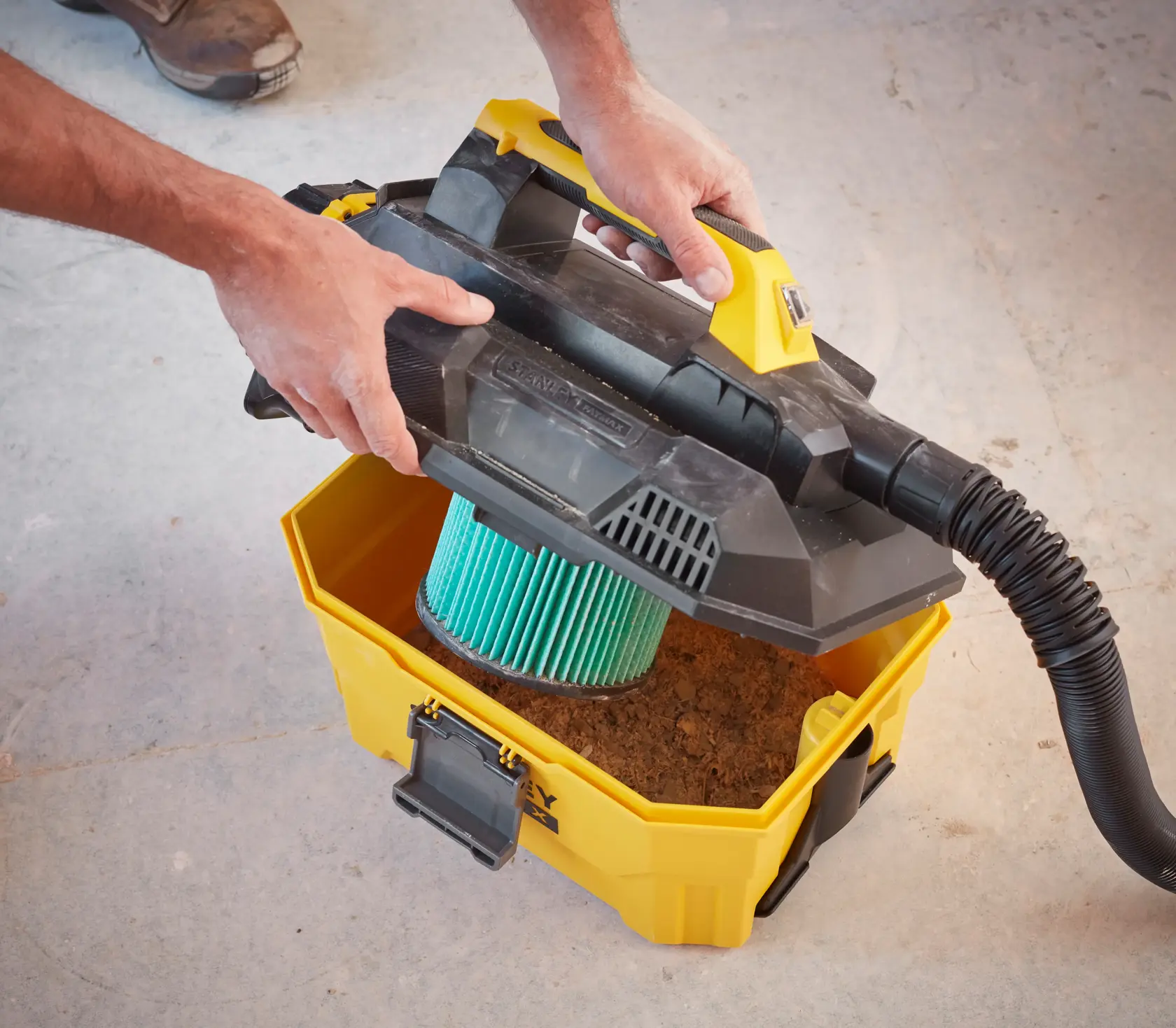 Photo of STANLEY SFMCV002B cordless wet/dry vacuum being opened, showing filter and dirt inside.