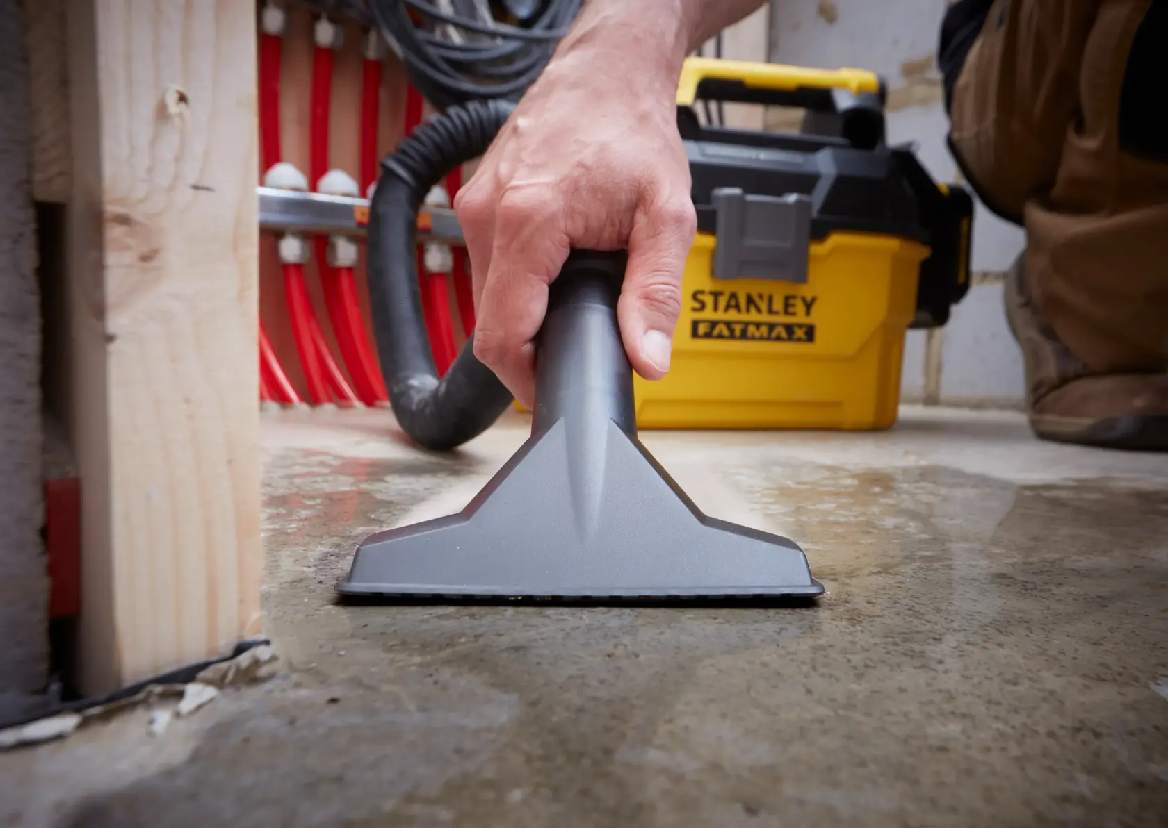 STANLEY SFMCV002B wet and dry vacuum used on a wet floor, close-up of nozzle and yellow vacuum unit.