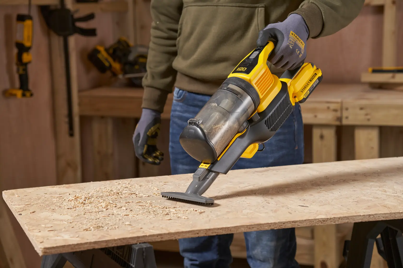 STANLEY SFMCVS001D1 handheld vacuum cleaner being used to clean wood shavings on a workbench, side angle.