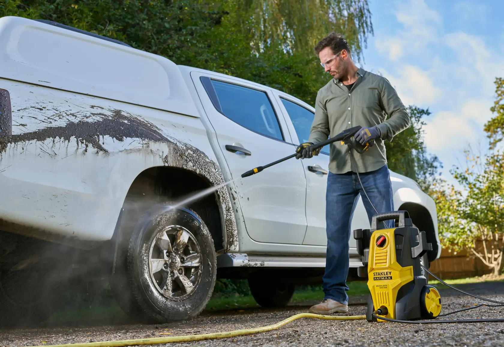 STANLEY SFMPW1740 pressure washer cleaning muddy white pickup truck outdoors.