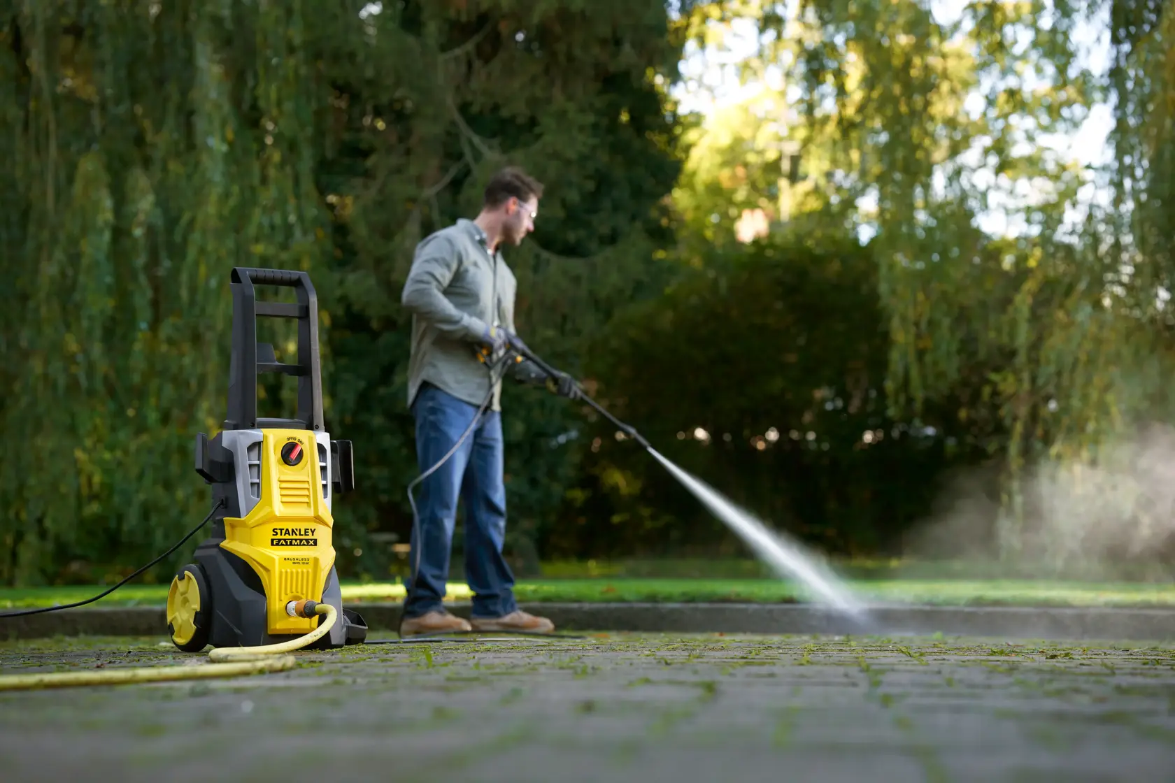 STANLEY SFMPW2000 pressure washer on wheels being used outdoors to clean pavement with water spray.