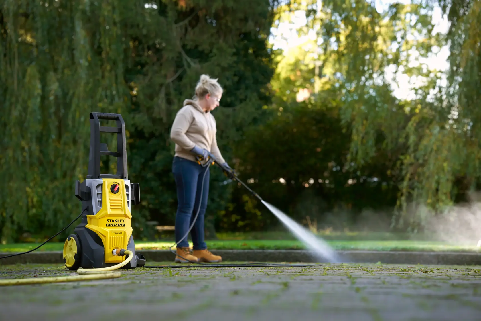 STANLEY SFMPW2000 pressure washer in use outdoors cleaning patio, yellow and black design visible in foreground.