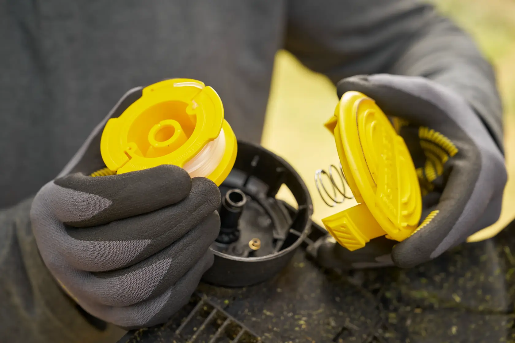 STANLEY STCST933B trimmer spool assembly photography, close-up of yellow spool and cover in gloved hands.