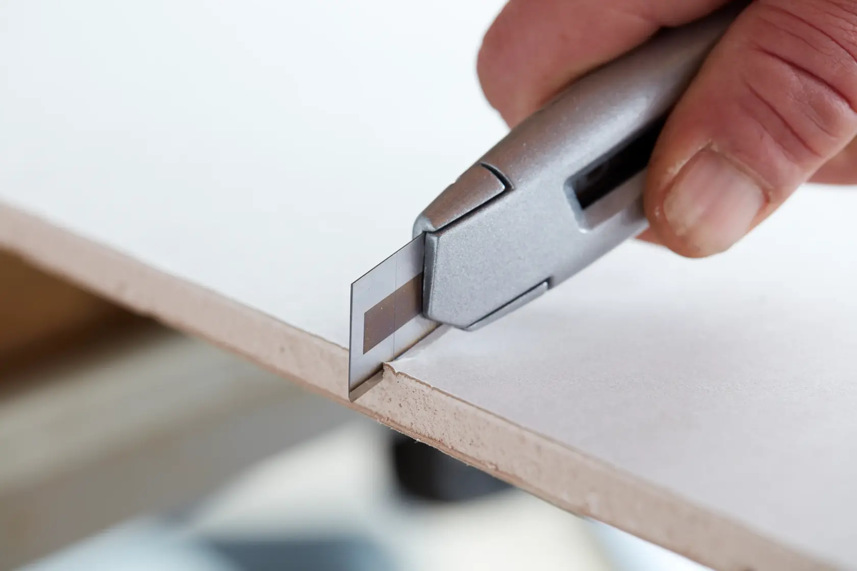 Photo of STANLEY STHT0-11818 utility knife cutting sheet material, close-up angle.