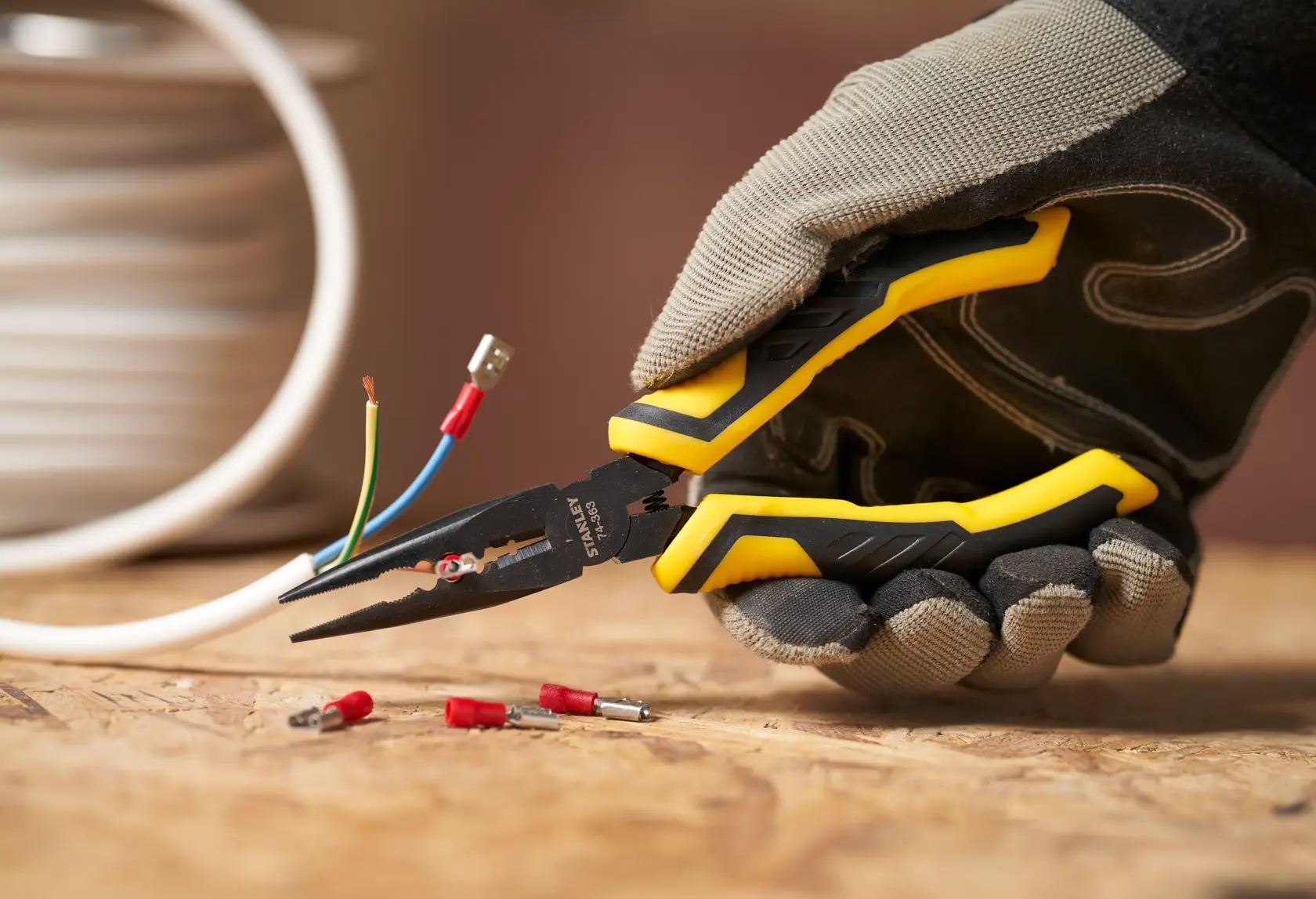 STANLEY STHT0-74363 wire stripper pliers with yellow-black handle in use, close-up on wiring task.