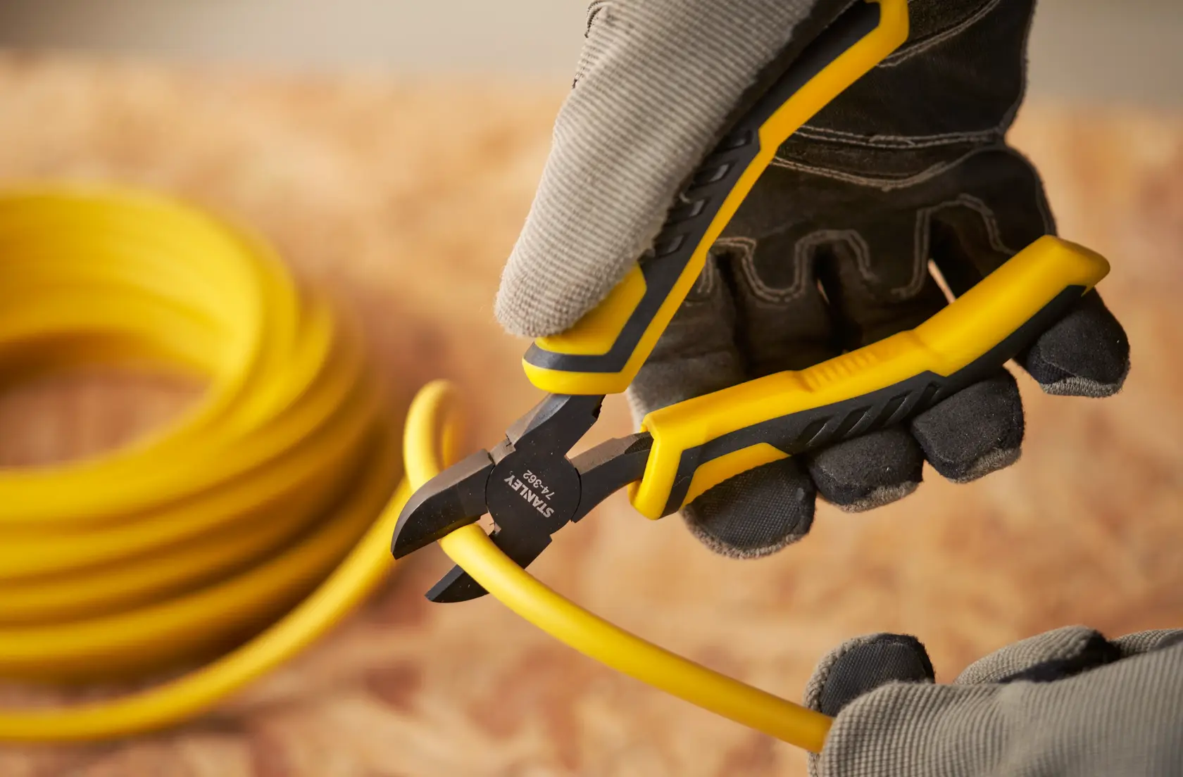 STANLEY STHT0-74455 diagonal cutting pliers cutting yellow cable, close-up outdoor photography.