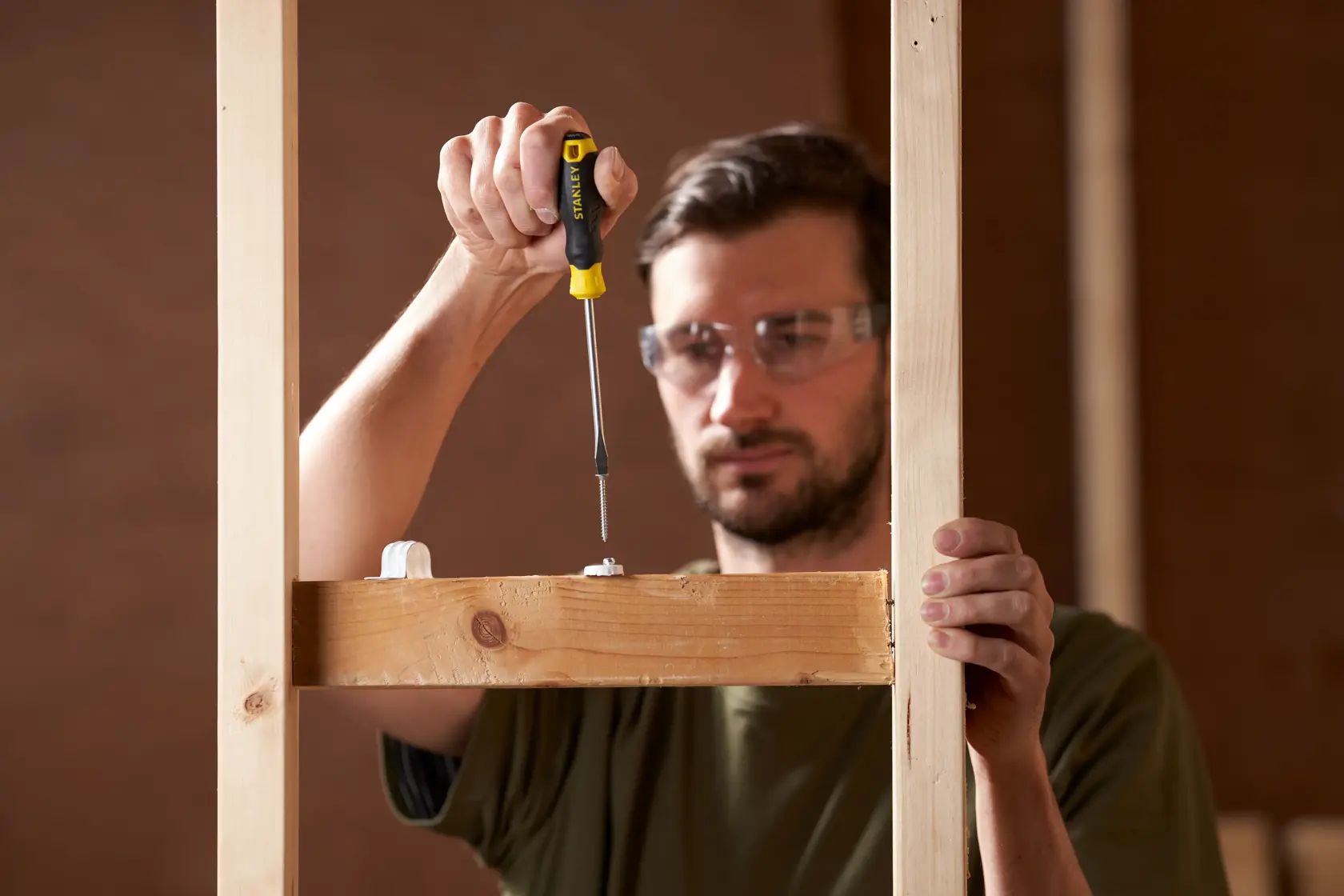 STANLEY STHT16146-0 screwdriver used on a wooden frame, close-up photography in construction setting.
