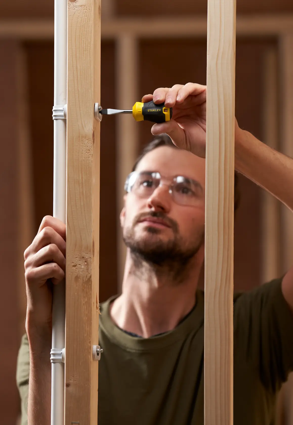 STANLEY STHT16147-0 screwdriver in use tightening a screw on wood framing, product photography.
