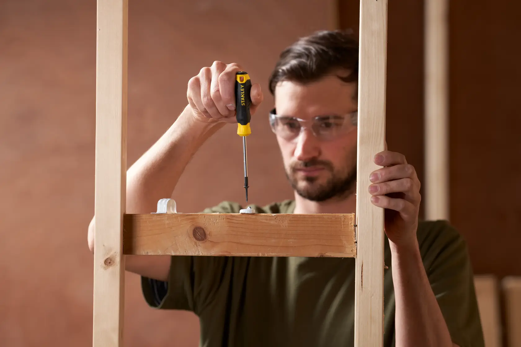 Photo of STANLEY STHT16155-0 screwdriver in use on wood frame construction, close-up view.