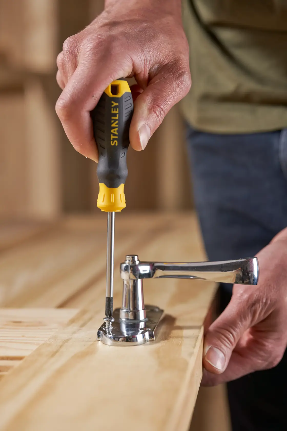 Stanley STHT16155-0 screwdriver used to fasten a door handle onto a wooden surface.