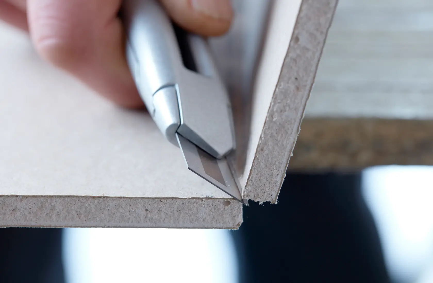 STANLEY STHT2-11818 utility knife cutting drywall panel, close-up view.