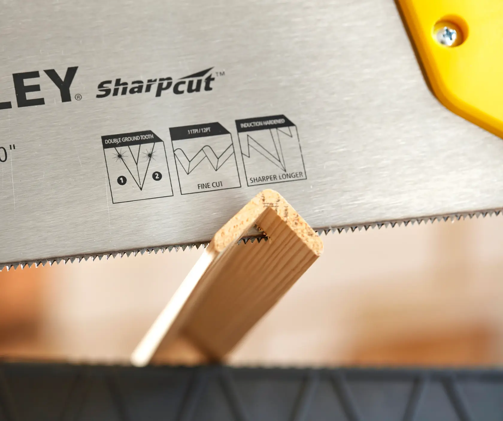 STANLEY STHT20372-1 hand saw blade close-up cutting wood, SharpCut teeth and yellow handle visible.