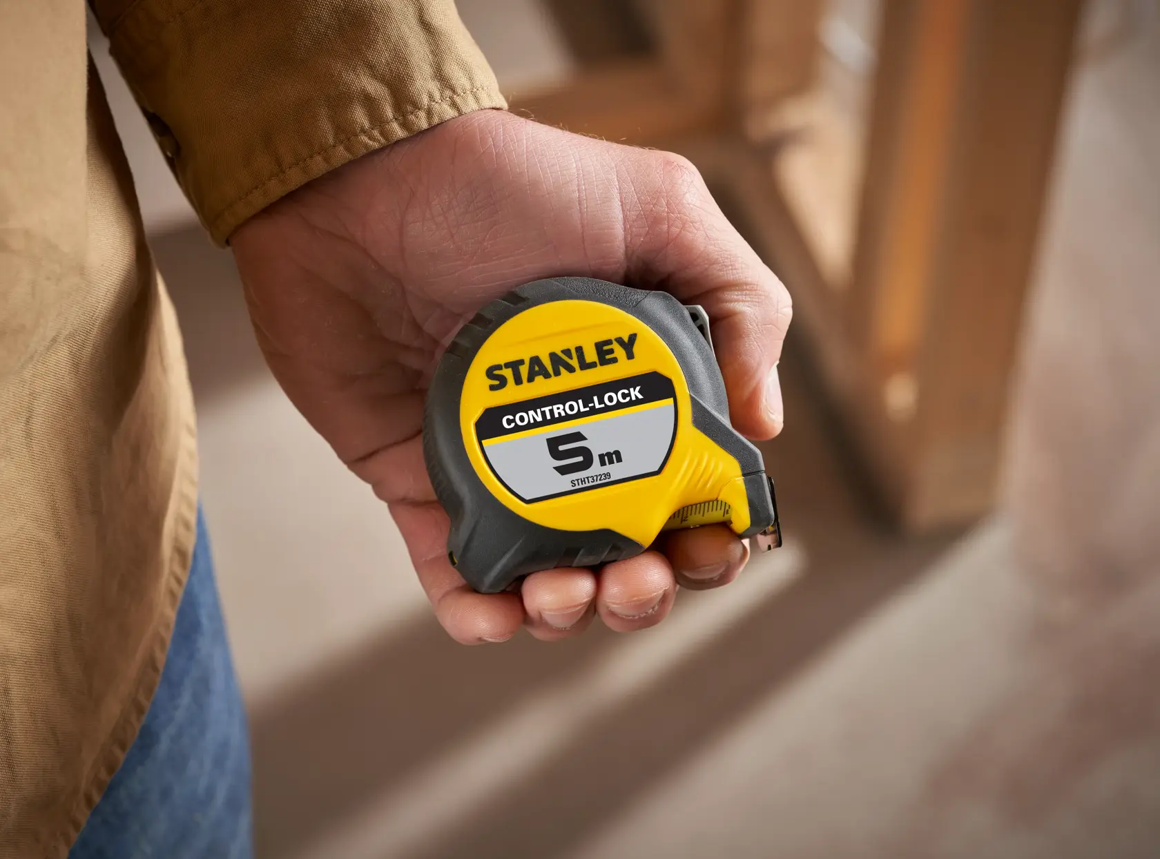 Photo of STANLEY STHT37239 tape measure, yellow and gray, 5m length, held in hand, product category: Photography.