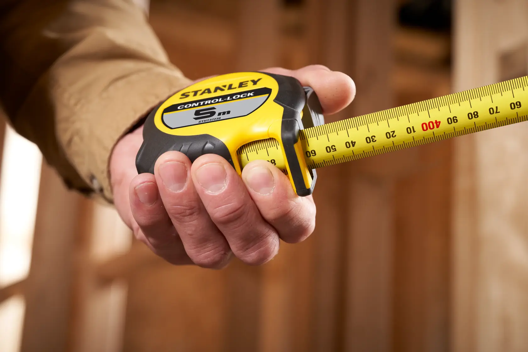 STANLEY STHT37239 tape measure held in hand, yellow and black housing, extended measuring tape.
