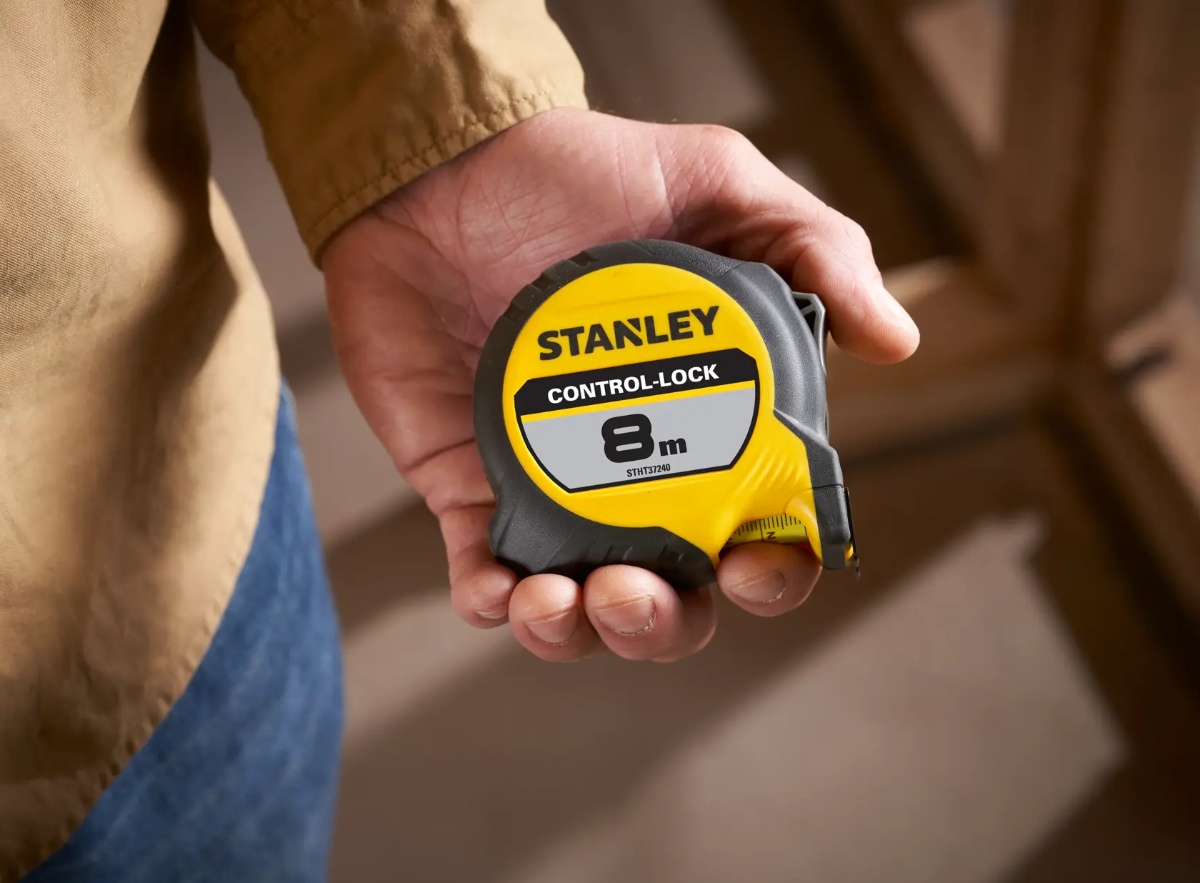 STANLEY STHT37240 tape measure with yellow and black casing in hand, 8m length, CONTROL-LOCK label visible.