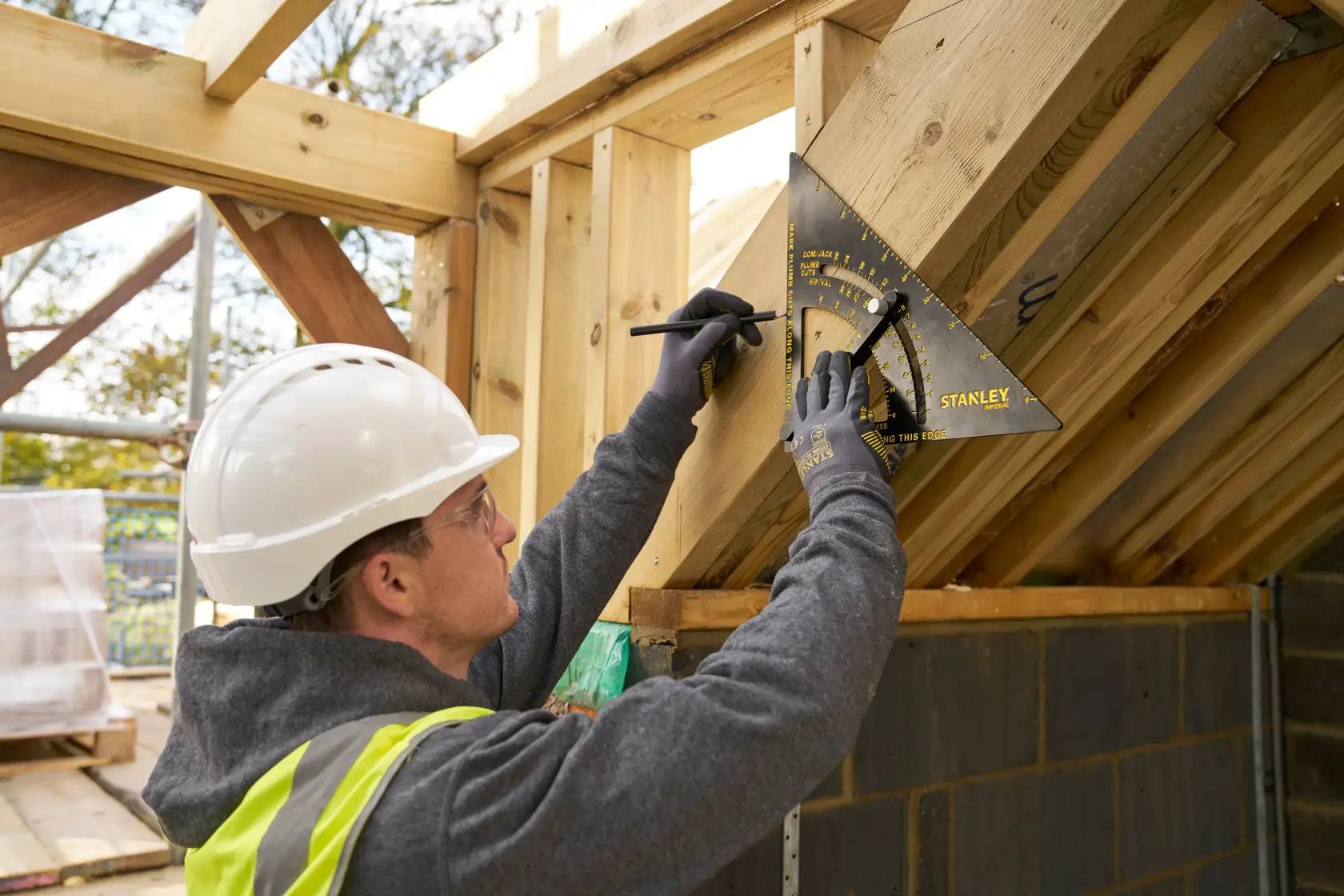 STANLEY STHT46055-0 rafter square used to mark wood angles at a construction site.