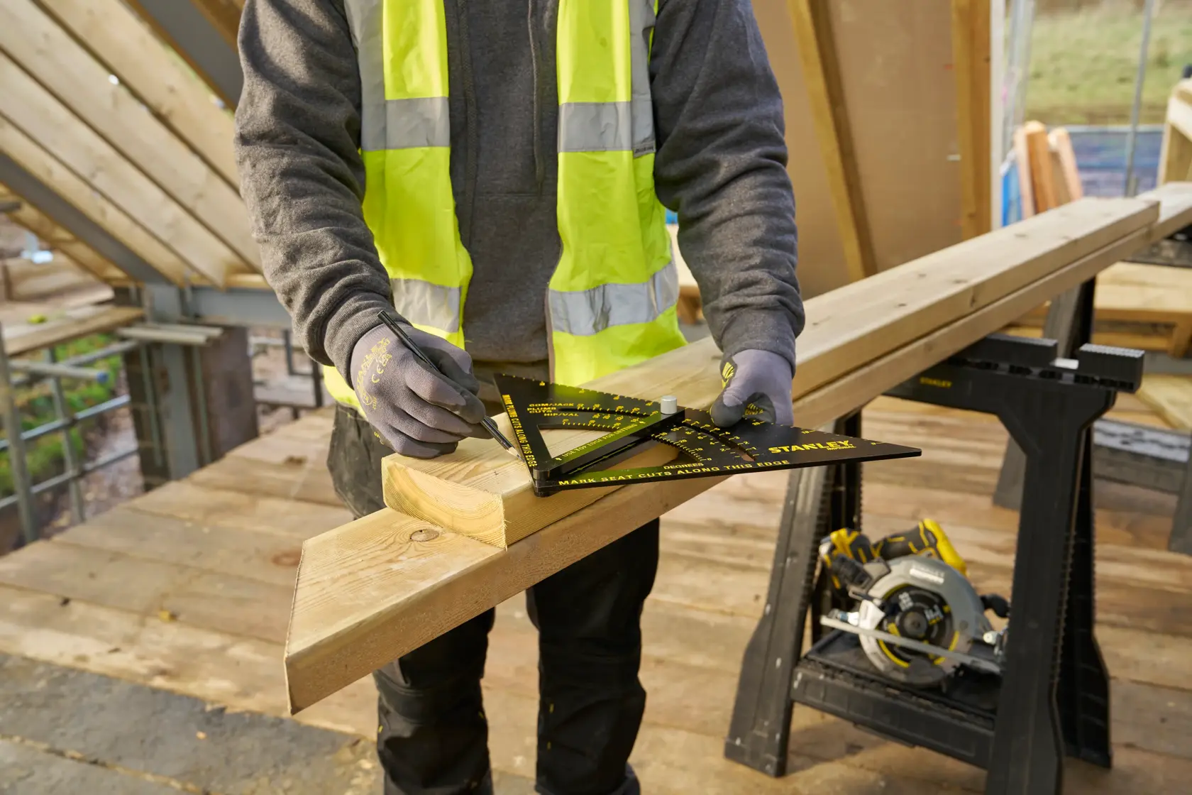 STANLEY STHT46055-0 rafter square in use on wood, construction site background, worker drawing marks.