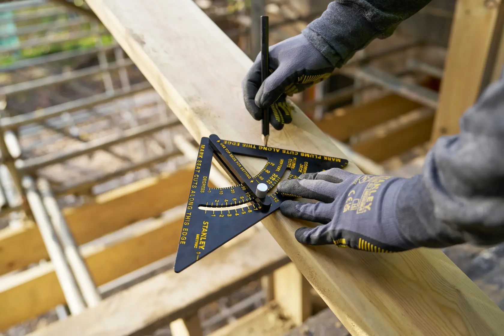 Photo of STANLEY STHT46056-0 carpenter's square tool in use on wooden plank, worker wearing gloves marking wood.