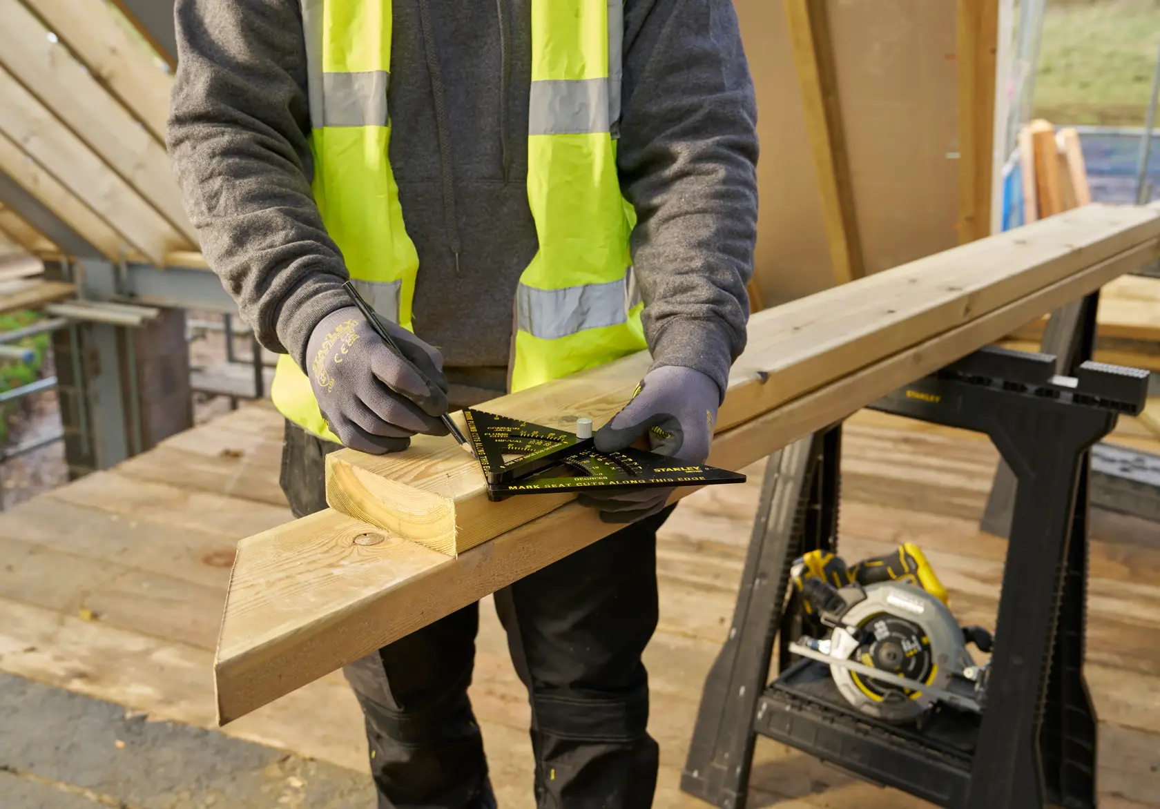 STANLEY STHT46056-0 rafter square on wood beam, angled view, used by worker for precise marking on construction site.