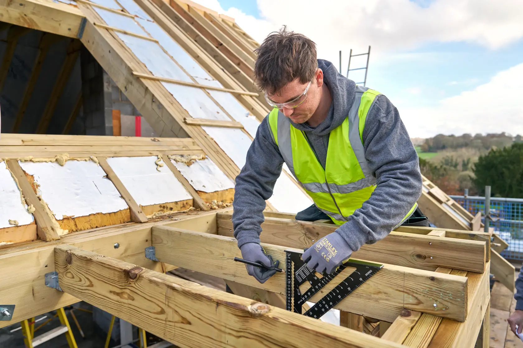 STANLEY STHT46102-0 roofing square used by a worker for wood measurement on construction site.