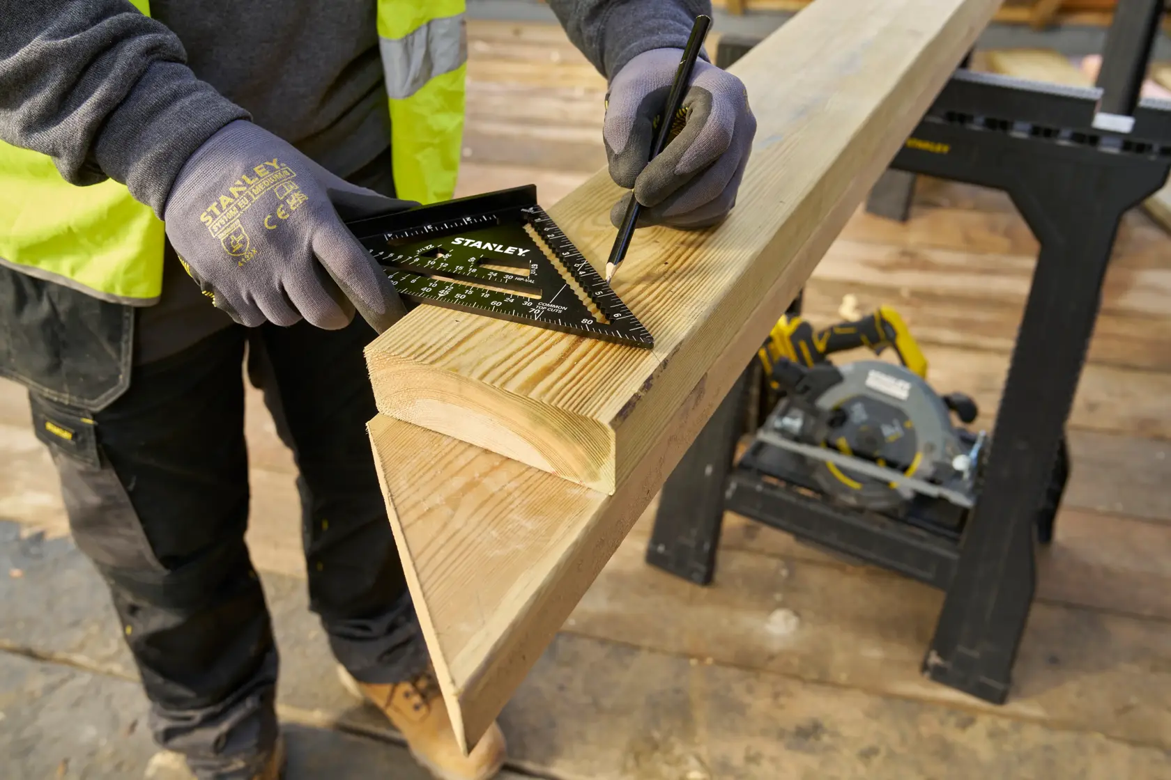 STANLEY STHT46104-0 rafter square used to mark a wooden beam on a jobsite, close-up view.