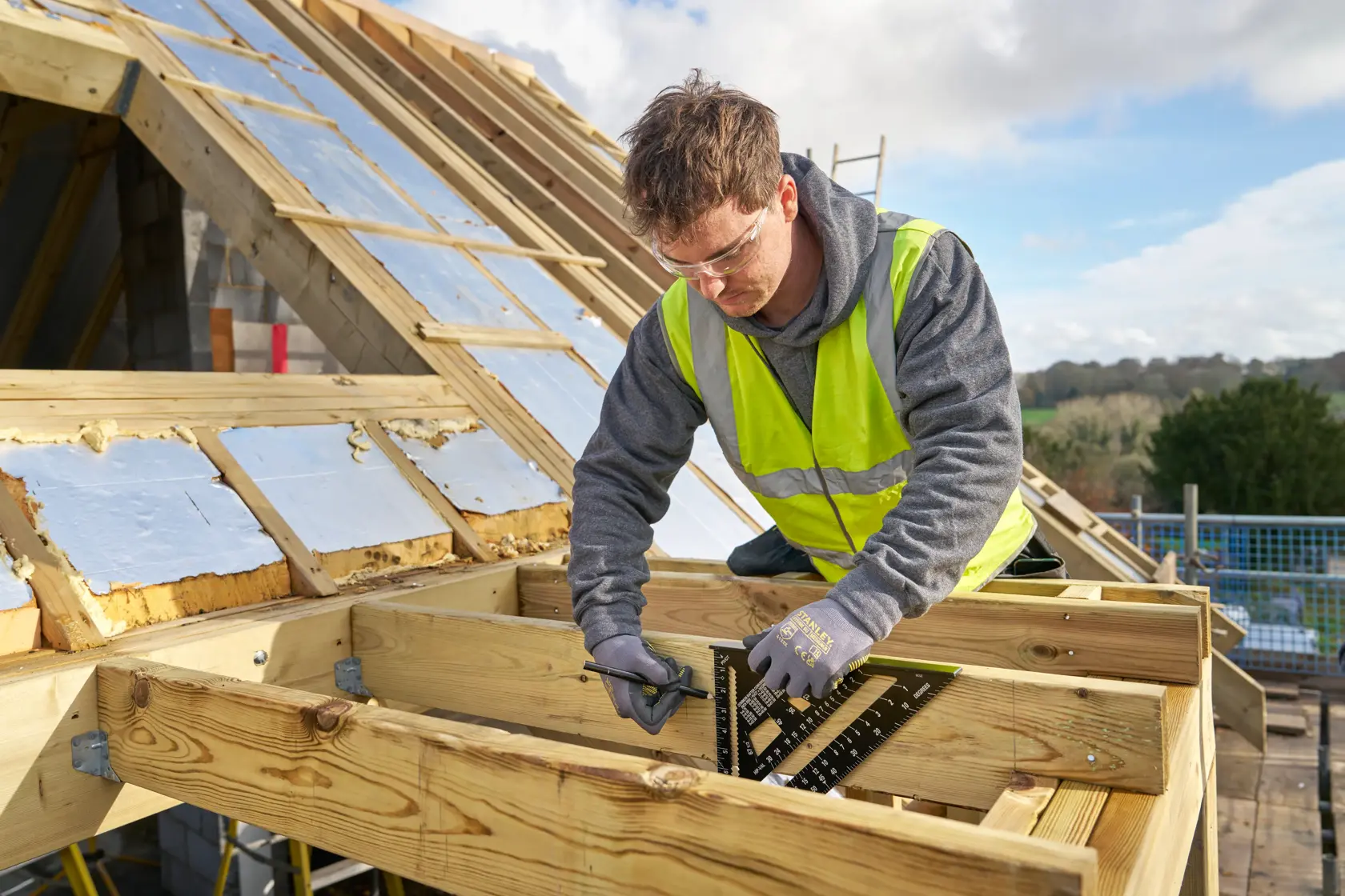 STANLEY STHT46105-0 roofing square used by worker for measuring on timber framework at construction site.