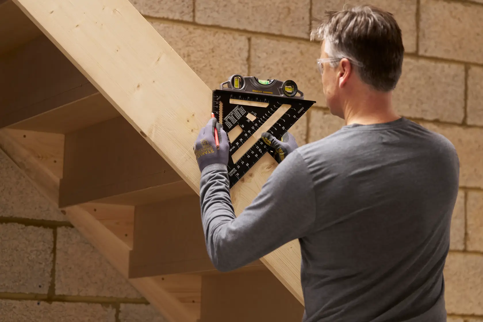 Photo of person using STANLEY STHT46105-0 combination square to measure and mark wooden staircase.