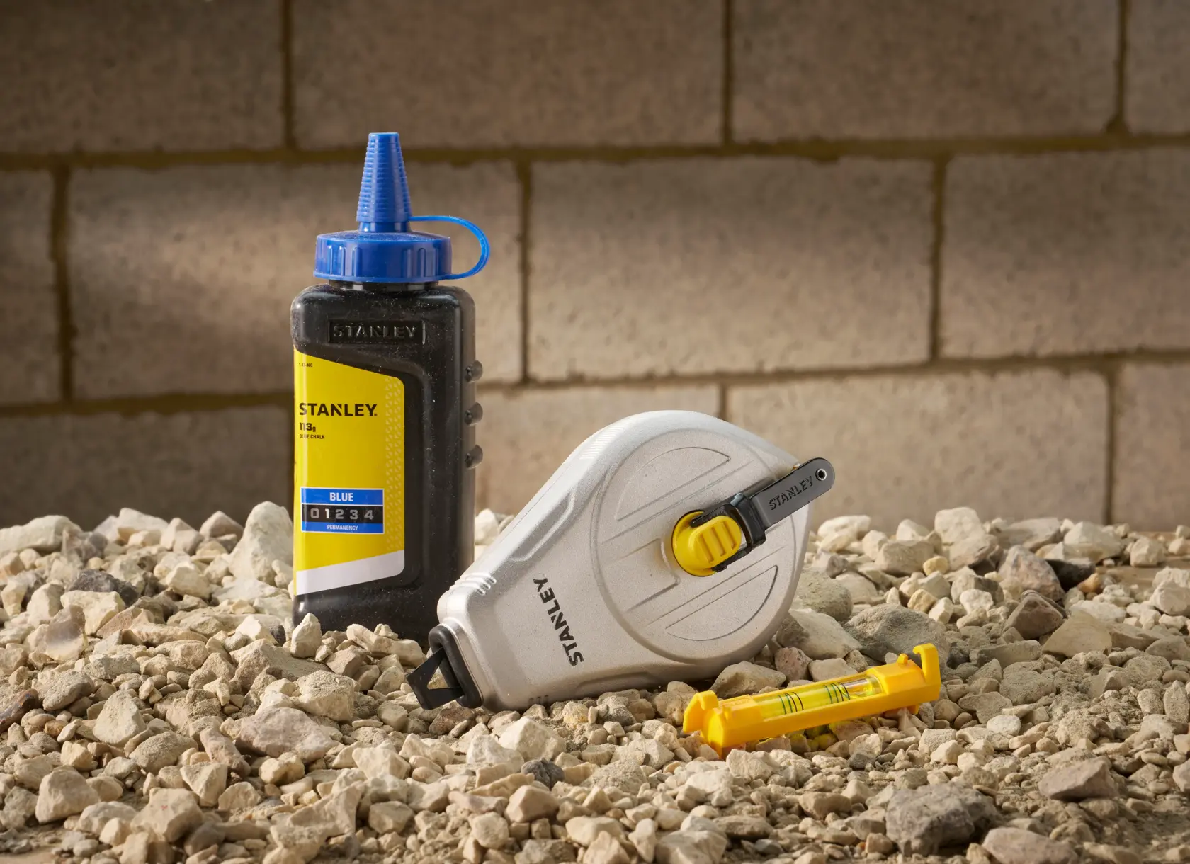 STANLEY STHT47111 chalk line set with chalk bottle and level on rocky ground.