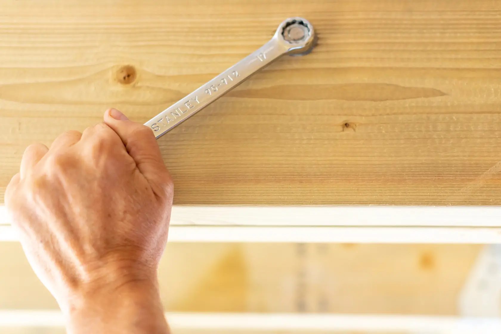 STANLEY STMT95788-0 ratcheting wrench in use on a wooden beam, close-up view.