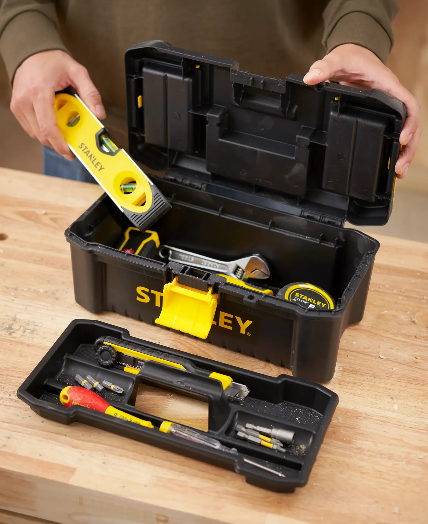 Photo of STANLEY STST1-75514 toolbox open on a workbench, showing compartments with tools and a yellow latch.