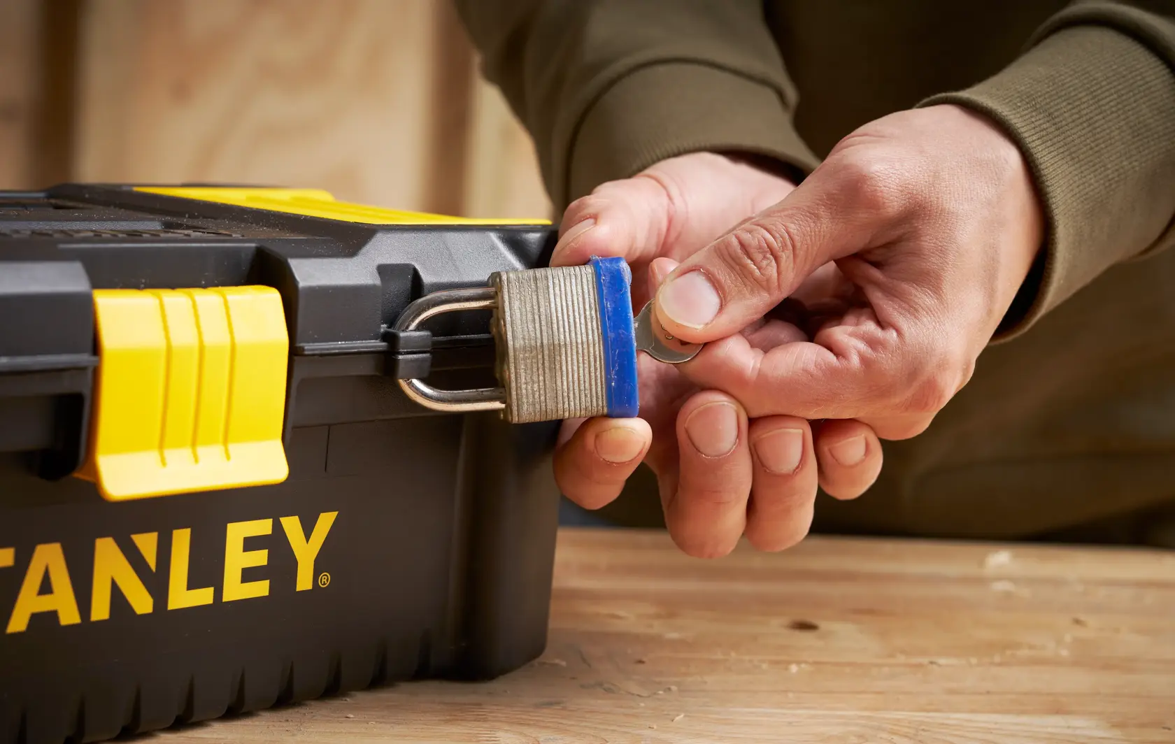 STANLEY STST1-75514 toolbox with yellow latch and padlock close-up, hands holding a key.