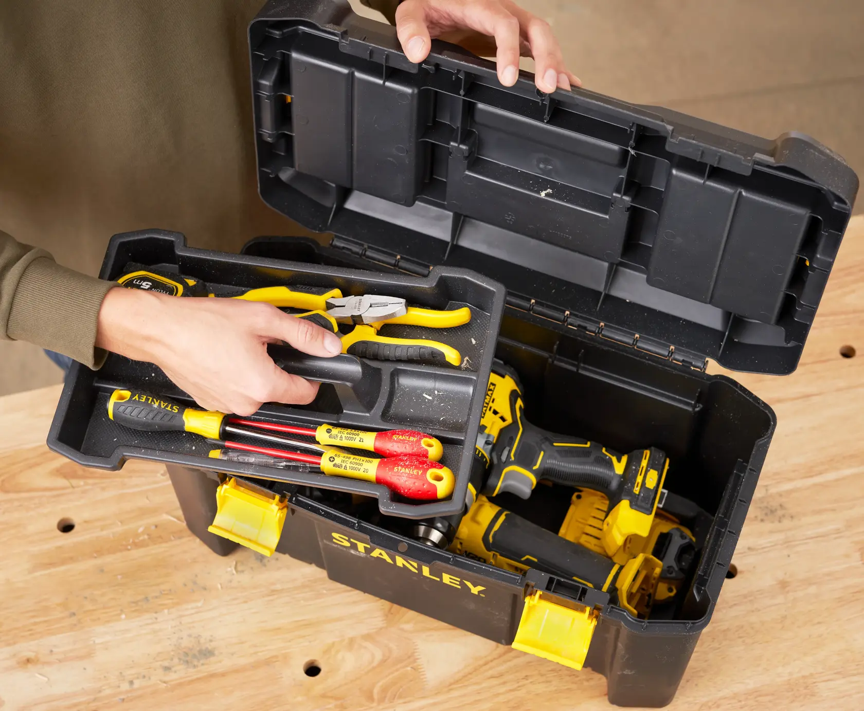 Photo of STANLEY STST1-75520 black toolbox with yellow latches, open to show assorted hand tools and power drill.